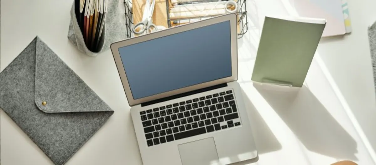 Biurko z leżącym laptopem i notatnikiem.