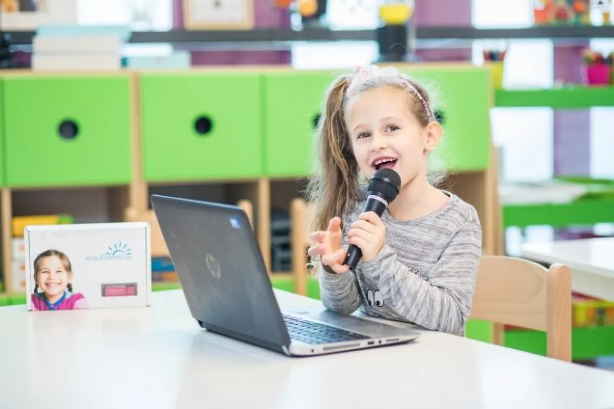 Śmiejąca się dziewczynka przy laptopie.