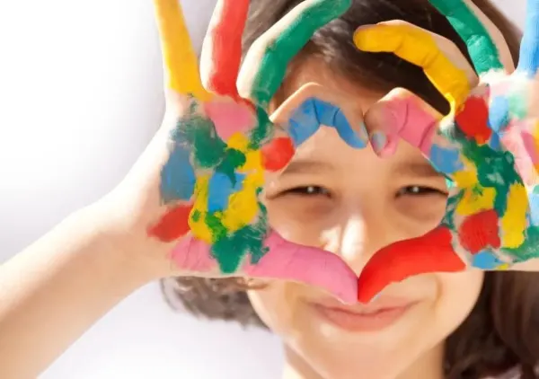 Dziecko z dłońmi ułożonymi w serce.