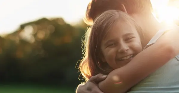 Uśmiechnięta dziewczynka w ramionach rodzica.
